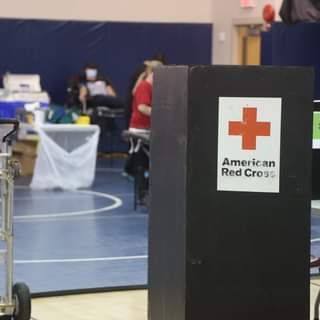 text reading American Red Cross. Indoor basketball gym with blue court.