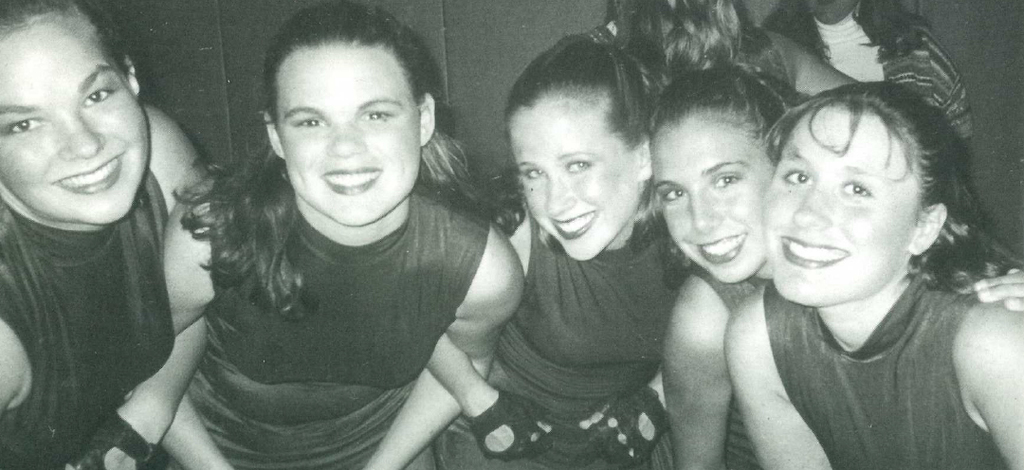 Three 1998 grads dressed up for a dance competition smiling with their girl friends.